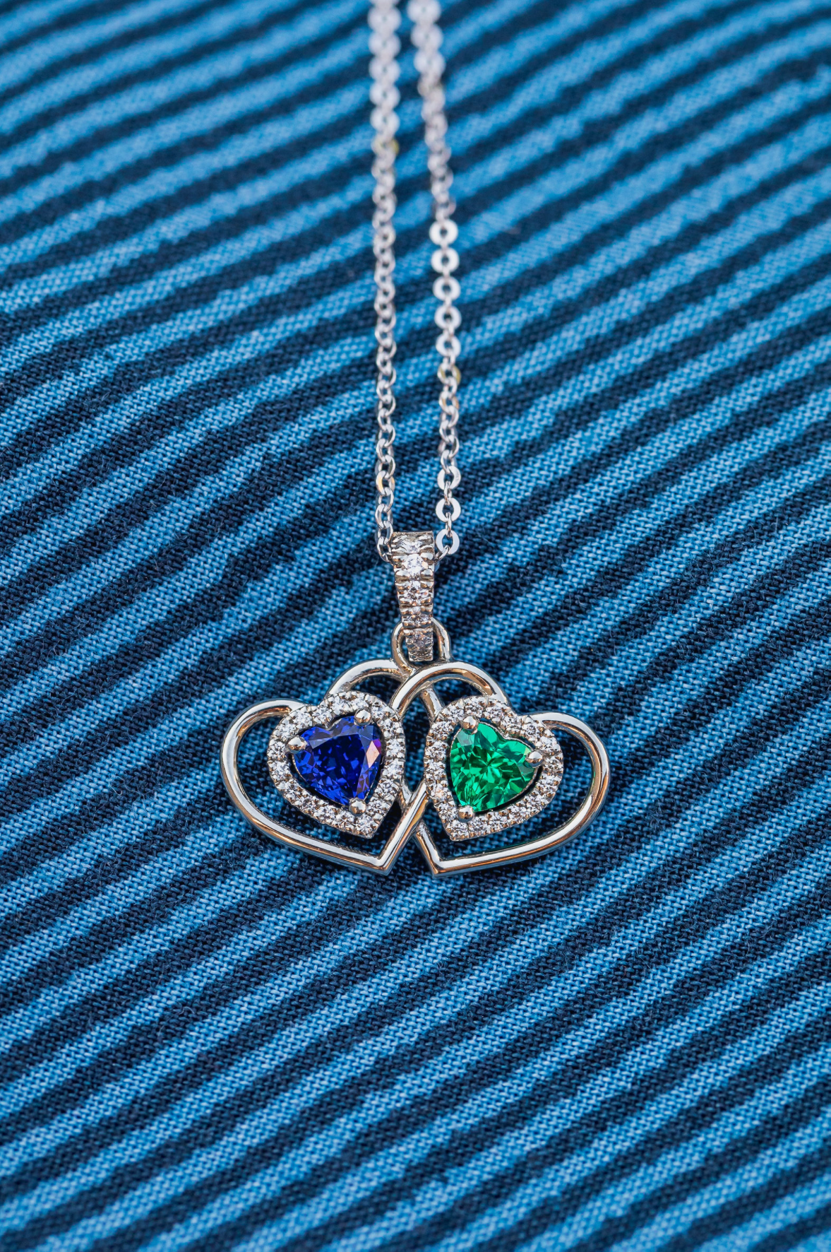 a pendant make with emerald and sapphire hearts in diamond halos